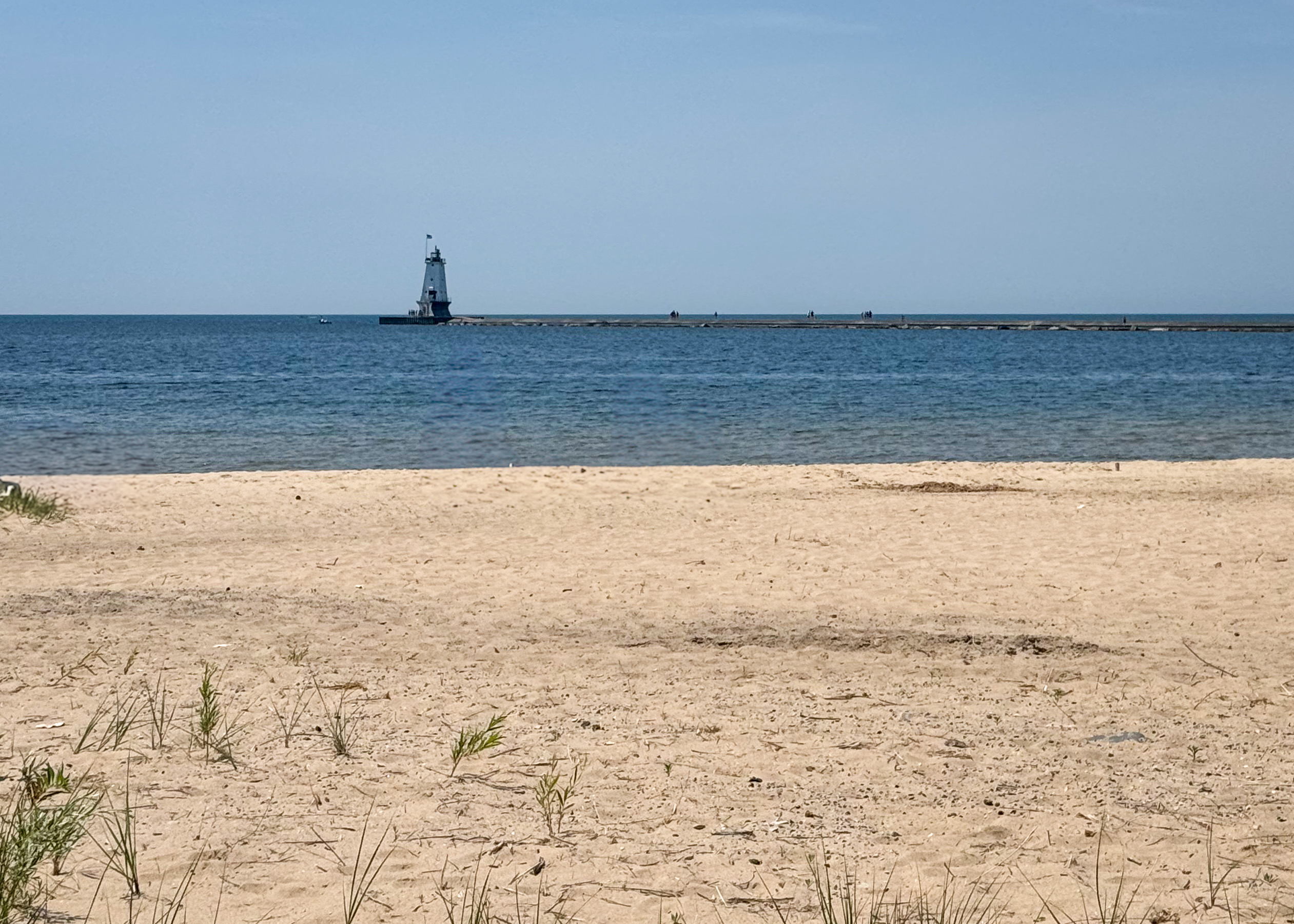 Lake Michigan beach with a lighthouse in the distance.
