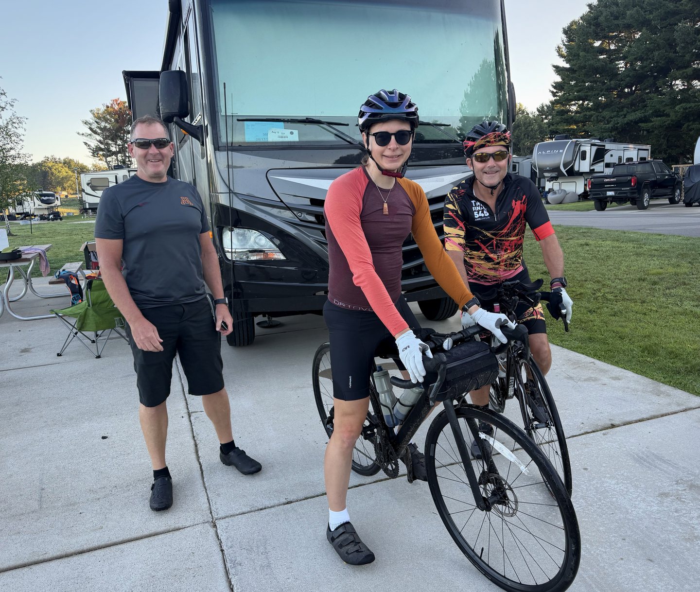 Two riders and a roadie standing with bicycles before the morning departure.