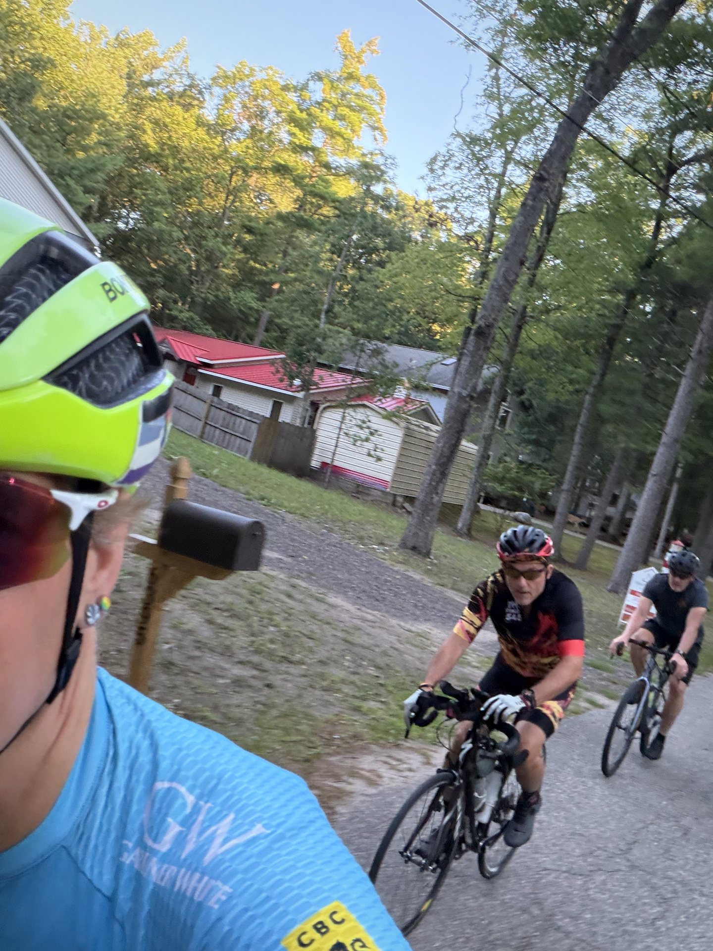 Three cyclists riding together in a moving selfie on a wooded road.