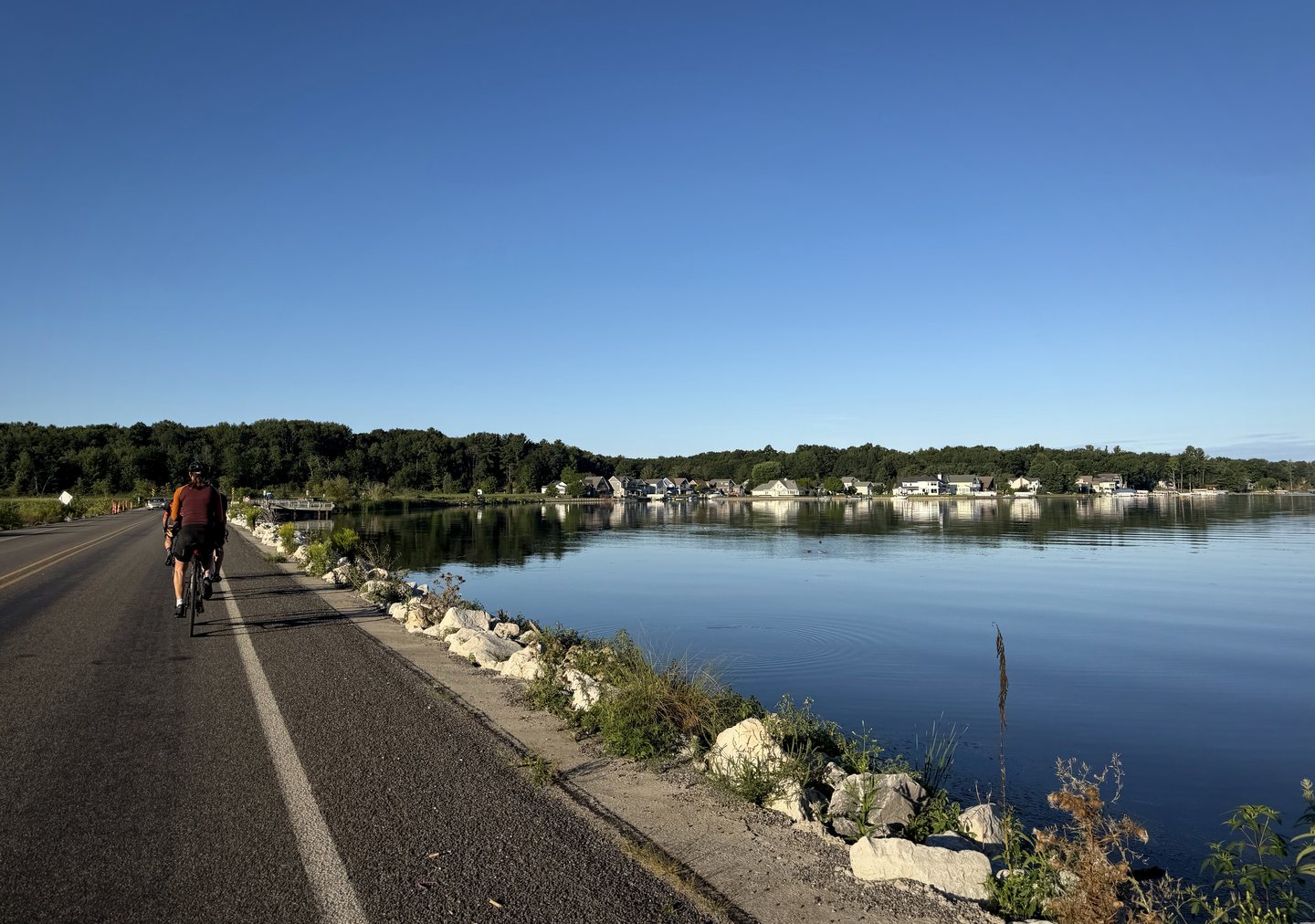 A Pedal for Pride cyclist riding beside calm blue water during the 2026 ride.