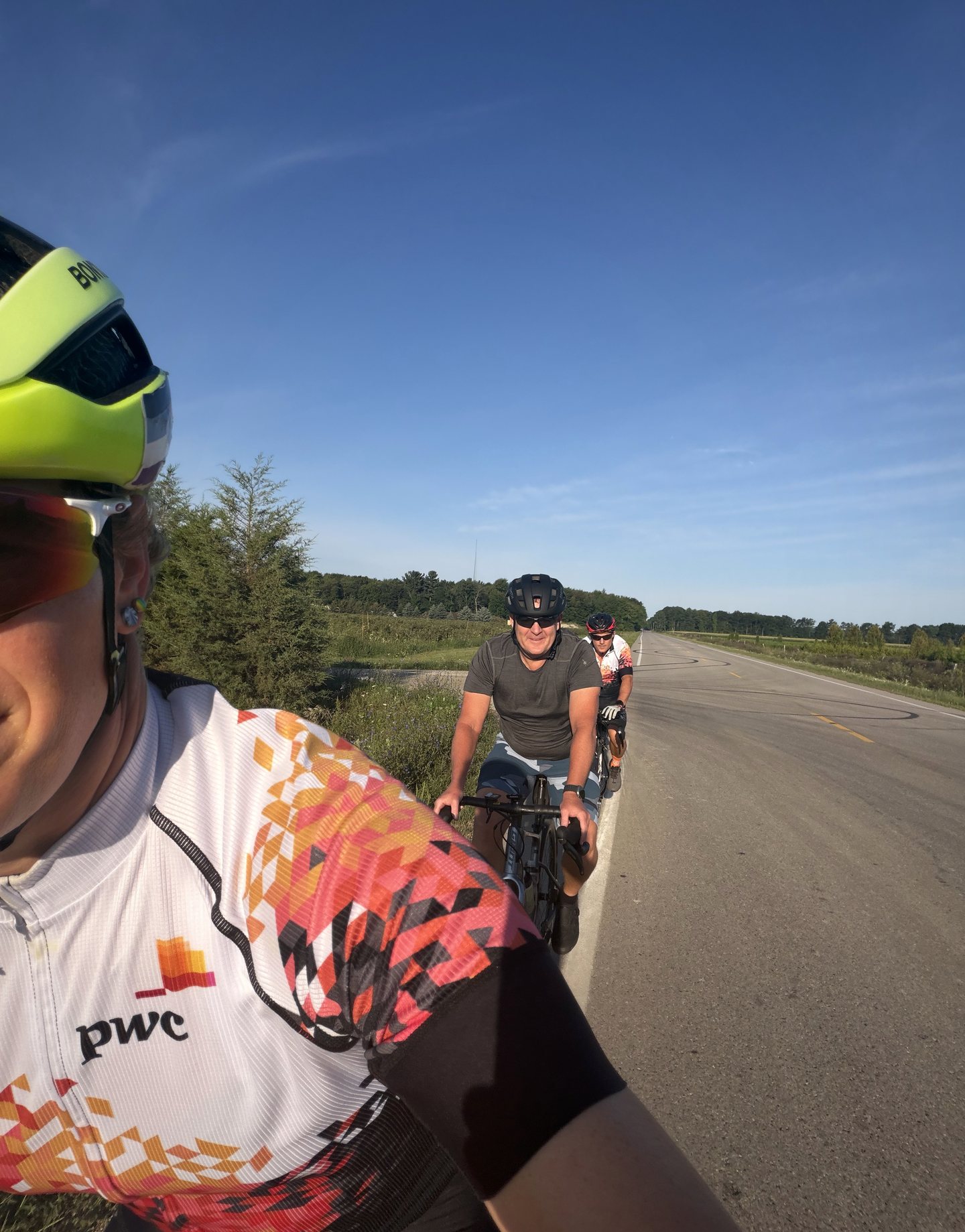 Three riders following one another on an open country road.