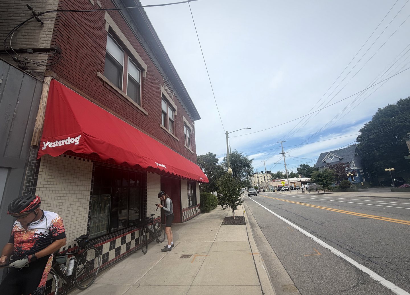 A cyclist stopped beside the red Yesterdog awning in East Grand Rapids.