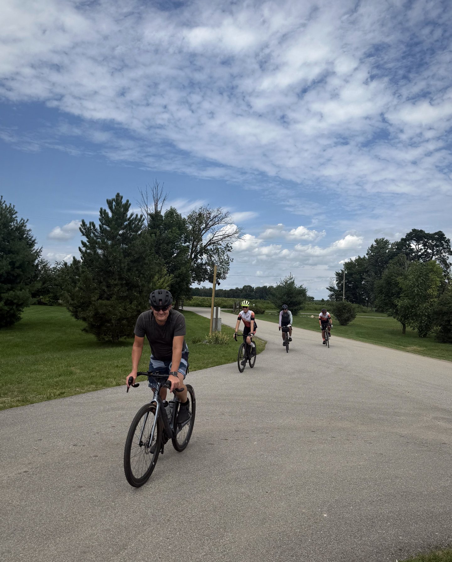 Four cyclists riding together through a green park.