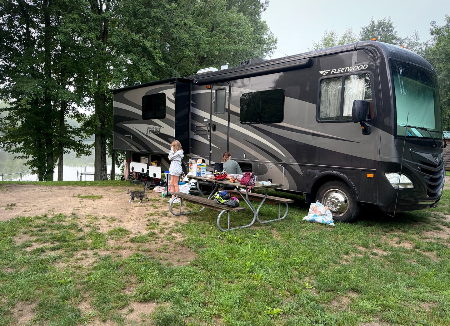 The Pedal for Pride motorhome parked beside the lakeside campsite as the support crew organized gear and supplies.
