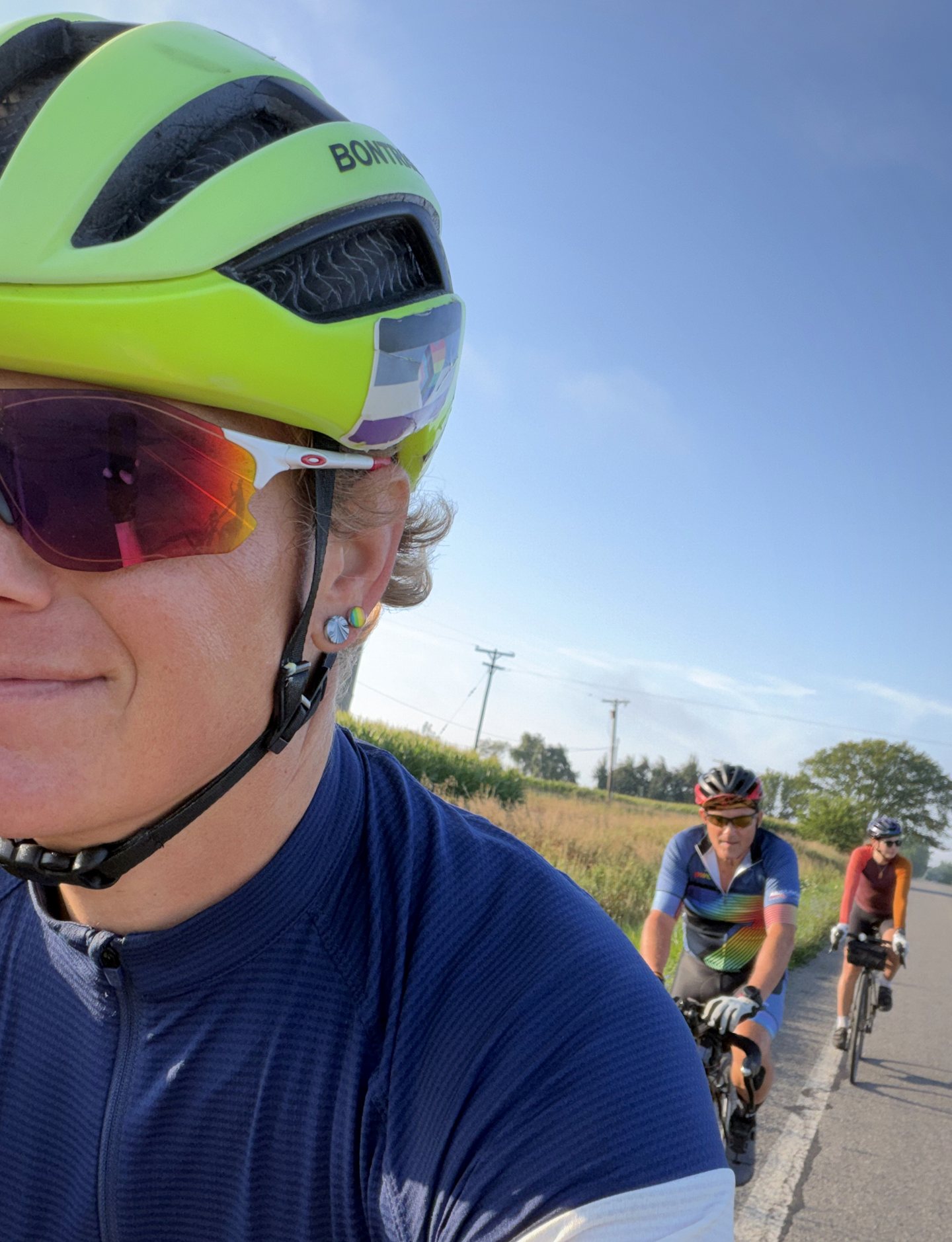 Three riders following one another on an open rural road.