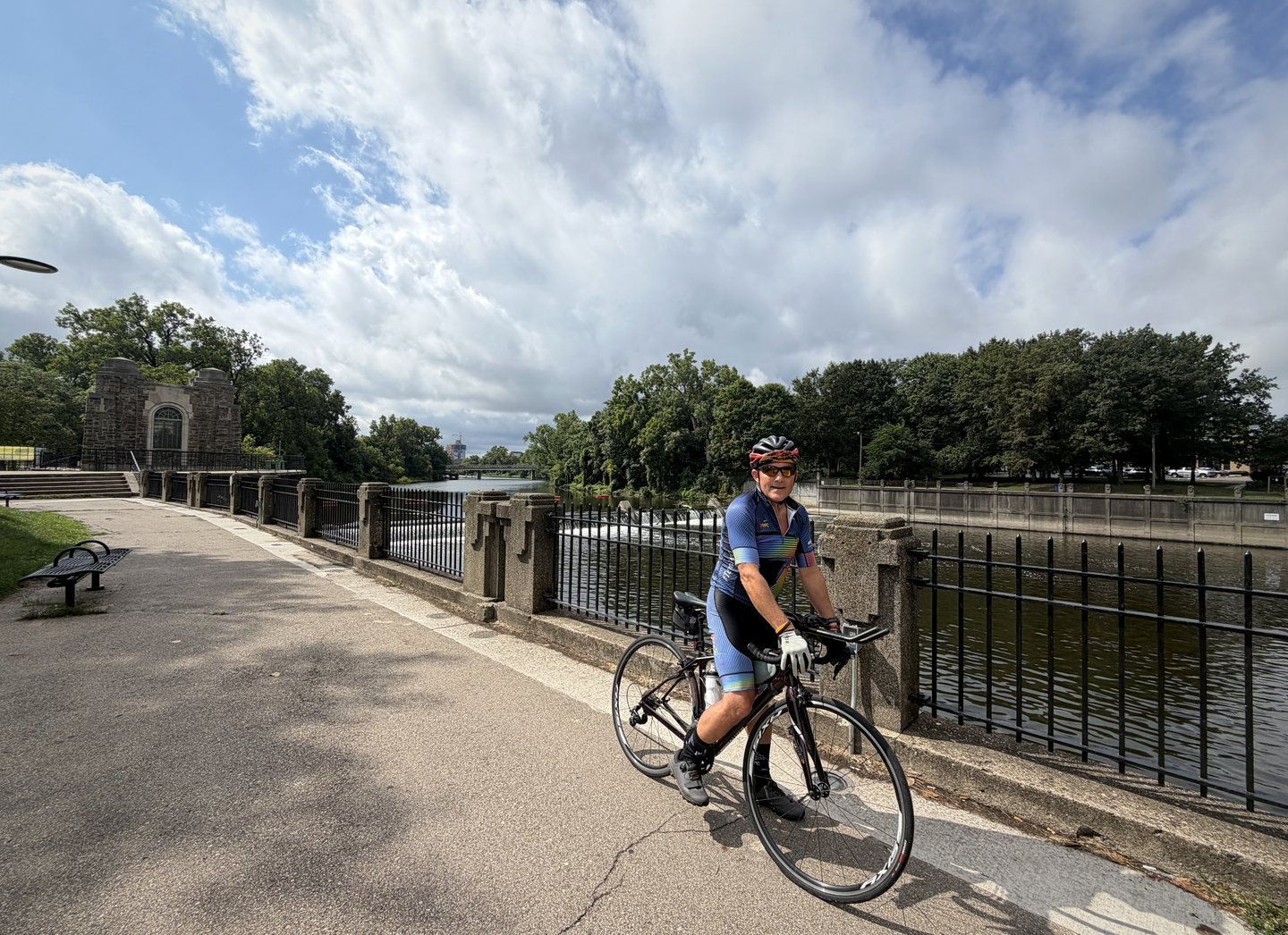 A smiling cyclist riding beside the water on the Lansing riverwalk.
