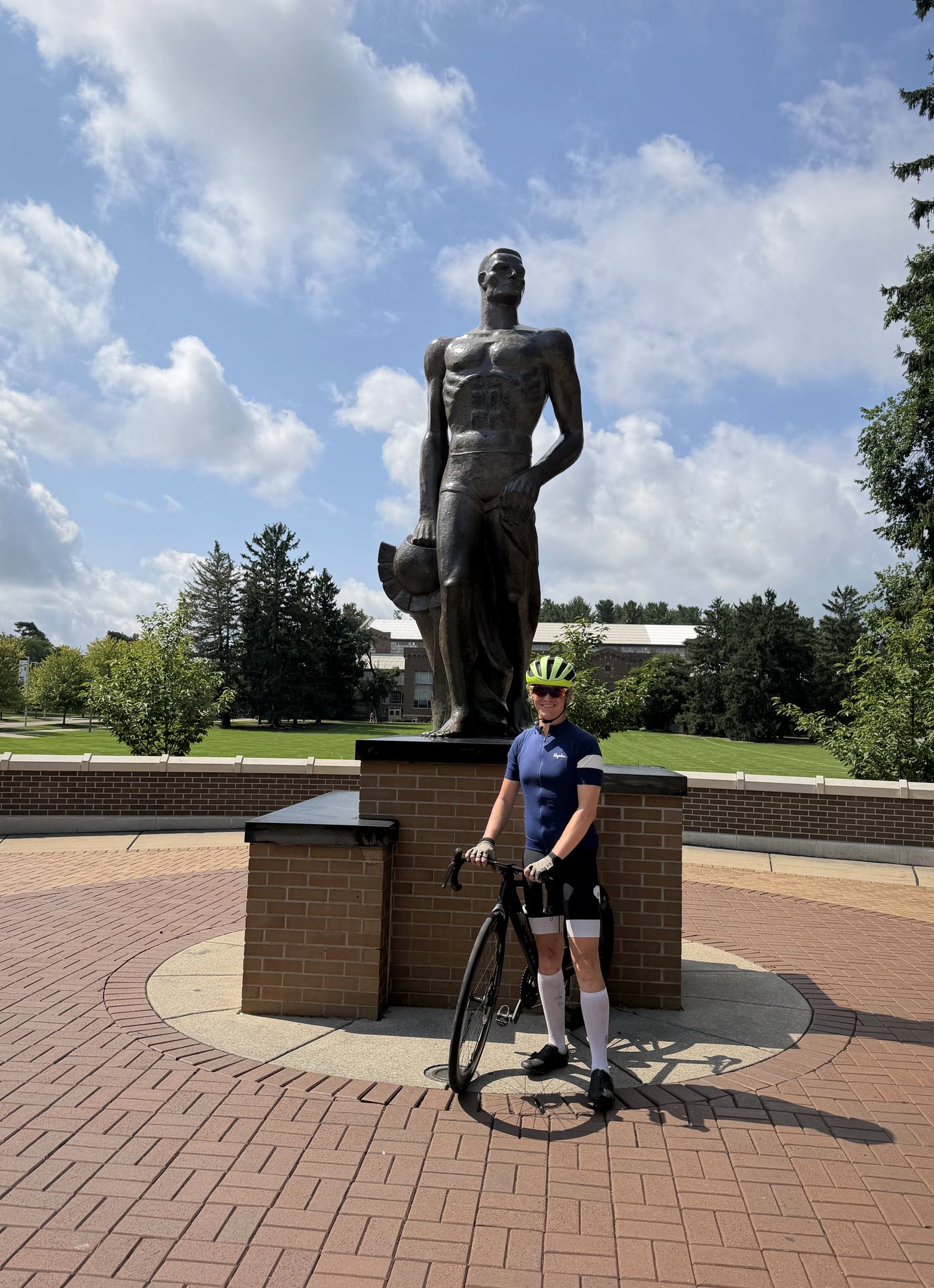 A cyclist posing with the Sparty statue at Michigan State University.