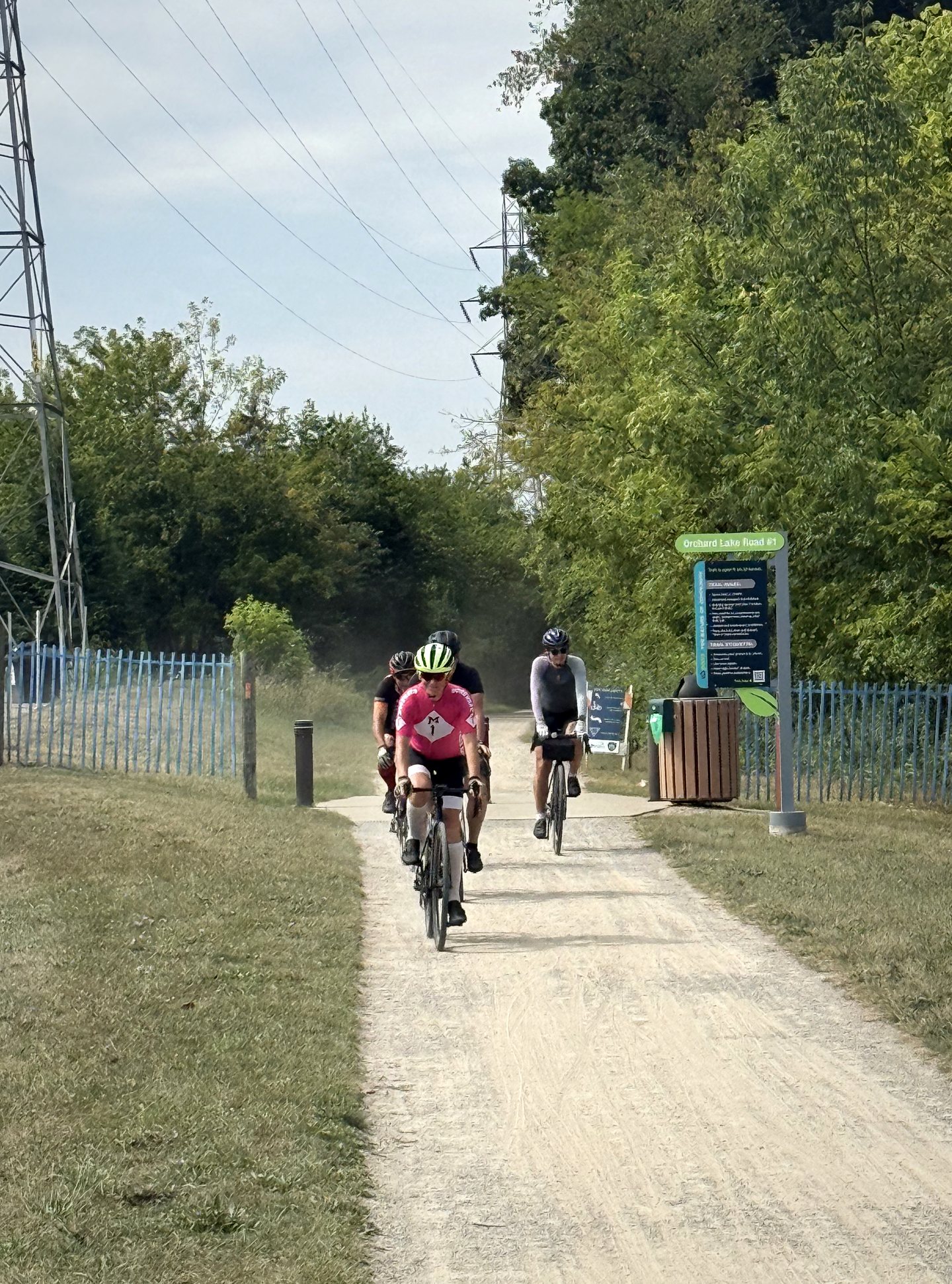 Four cyclists entering a paved park trail together.